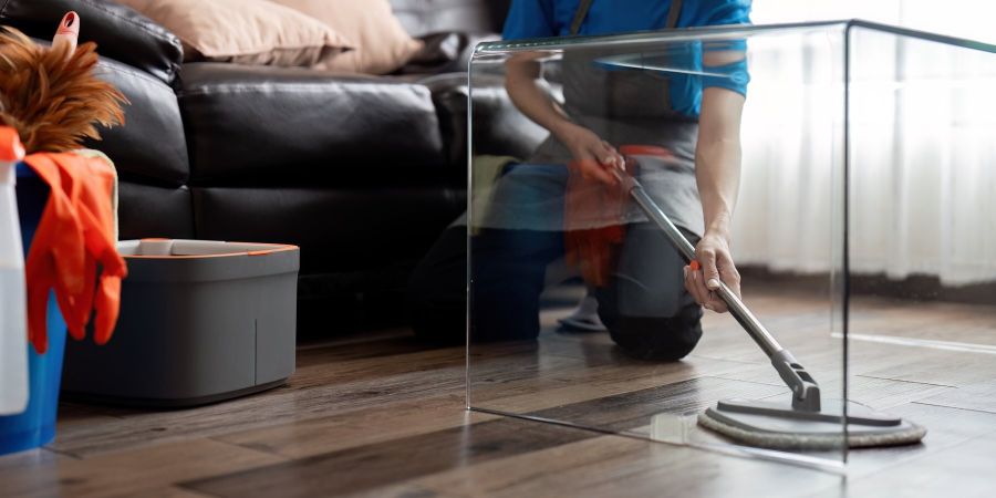 Man cleaning with mop under the coffee table